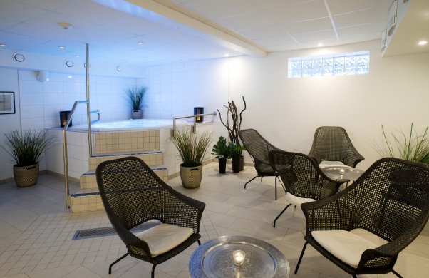 Bild på relaxen. I förgrunden syns svarta rottingfåtöljer med små silverbord. I bakgrunden syns jacuzzin.